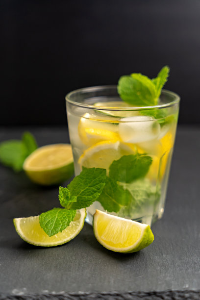 带有柠檬和薄荷青柠的清凉饮品玻璃杯，背景为深色。美食照片。夏季柑橘柠檬水概念。图片下载