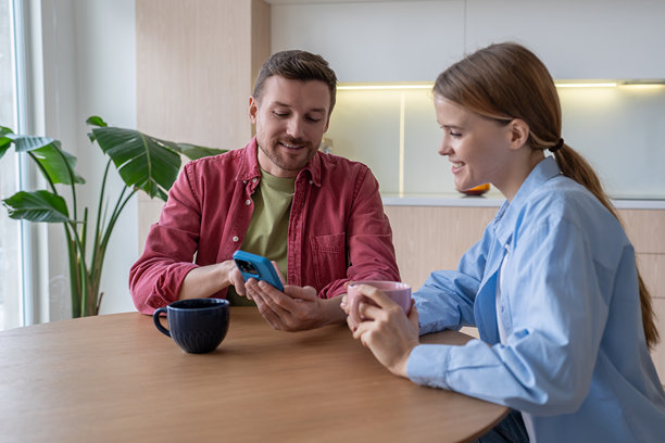 恩爱夫妻在家中一起喝咖啡，查看手机里的照片，享受共度时光。图片下载