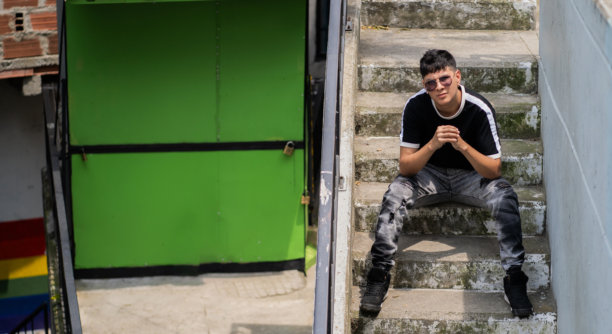 城市年轻男子在户外的梯子上坐着，态度放松 - 股票照片。图片下载