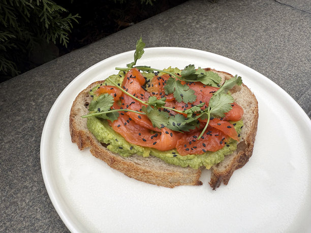 黑麦面包上的轻盐鱼三明治，配以香菜、捣碎的鳄梨和黑芝麻。街头美食概念。手工拍摄的移动照片，非人工智能生成。图片下载