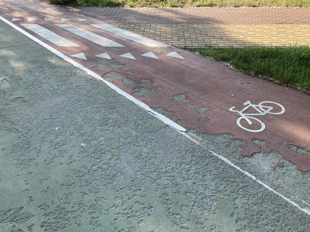 一段铺设的自行车道照片，带有单向或方向指示，禁止自行车进入的标志，可能禁止左转，并显示出磨损迹象，拍摄于车辆内部。图片下载