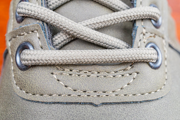 特写照片展示了绒面质感的鞋面，重点关注鞋带和缝线细节，系成传统的结，强调设计和优质工艺。图片下载