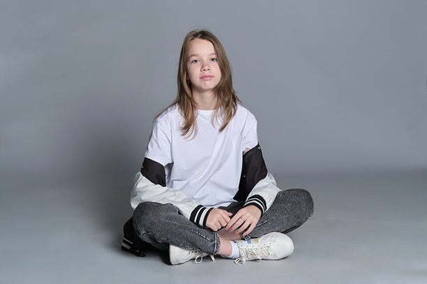 一个穿着休闲服的女孩盘腿而坐，沉浸在思考中。这张图片突显了纯真与逐渐成熟的结合，象征着自我发现和个性的旅程。图片下载
