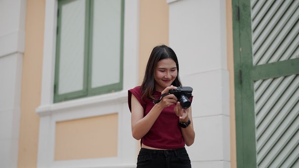 亚洲女性在户外环境中微笑着查看相机中的照片图片下载