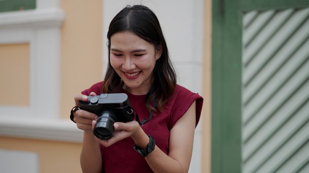 亚洲女性微笑着查看相机中的照片，满脸幸福与喜悦。图片下载