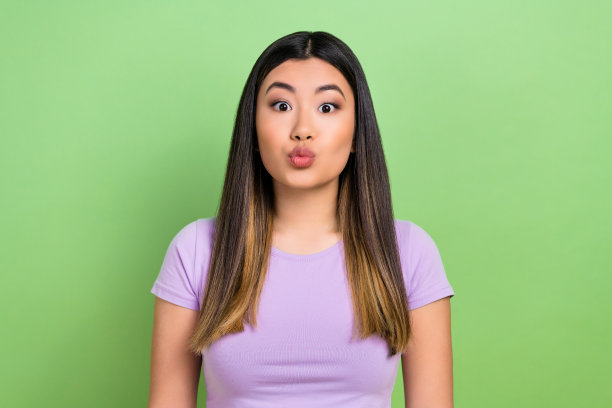 可爱的年轻越南华裔女士的照片肖像，丰满的嘴唇，亲吻姿势，穿着时尚的紫色服装，背景为绿色。图片下载