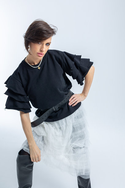 身穿黑色毛衣和浅灰色裙子的美丽模特，背景为白色。高端时尚。竖版照片。图片下载