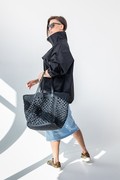 穿着黑色风衣和浅蓝色裙子的优雅女性，背景为白色。时尚女性风格。摄影棚拍摄。竖版照片。图片下载