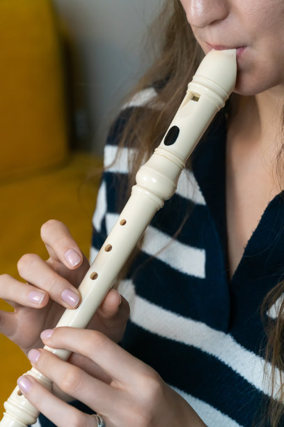 特写镜头展示了一位音乐家熟练地演奏录音管，演奏出迷人的旋律，突显了艺术才华和音乐表现力。竖版照片图片下载