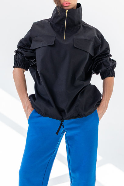 穿着黑色风衣、蓝色裤子和海军帽的优雅女性，背景为白色。时尚女性展现海洋法式风格。工作室摄影。竖版照片。图片下载