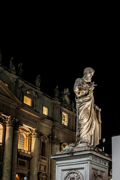 梵蒂冈城，罗马，意大利，圣彼得大教堂前的圣彼得雕像与夜空相映，竖版照片。图片下载