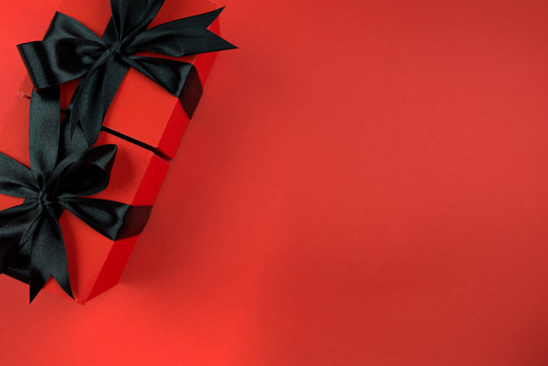 红色背景上孤立的红色礼品盒，配有黑色缎带蝴蝶结的俯瞰全景照片，留有空白空间。图片下载