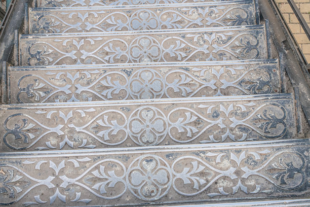 古董金属楼梯，带有花卉精美设计，向上延伸，拍摄于历史建筑的自然照片，可能是在阴天的室内拍摄。图片下载