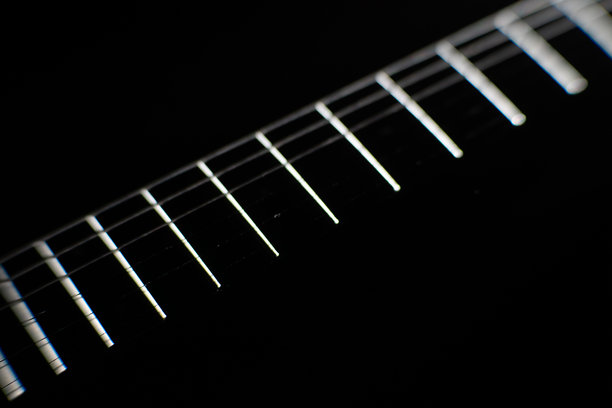 电吉他拾音器的特写图像，琴弦在模糊的黑暗背景中清晰可见。浅景深风格的照片，人工照明投射出柔和的阴影。图片下载