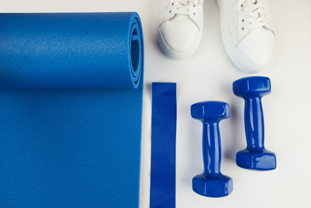 运动配件的概念。白色运动鞋、蓝色哑铃、蓝色瑜伽垫及其他运动器材的照片。图片下载