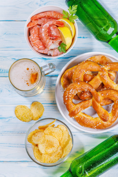 一张生动的照片，展示了一杯啤酒，周围是各种小吃和快餐。图片下载