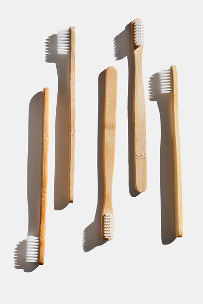 阳光下白色背景上的环保木质牙刷，柔软的彩色刷毛。极简设计照片，可持续卫生理念，零废弃生活方式，环保意识生活，强烈阴影。图片下载