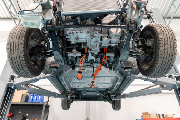 电动汽车底部的详细视图，电池已被拆除，暴露出连接到车载充电器（OBC）和电动机的高压电缆。重点关注电动汽车基础设施、维修和绿色汽车技术。图片下载