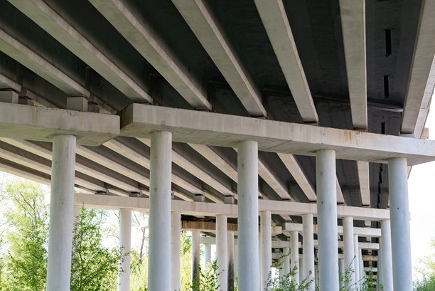 底部视角的抽象工业照片，展示了混凝土支柱的道路桥。图片下载
