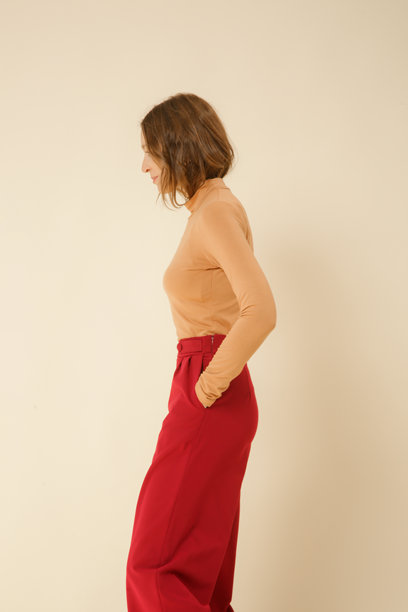 一系列年轻女性模特的工作室照片，穿着简单而美丽的服装，米色高领上衣和红色宽腿裤。图片下载