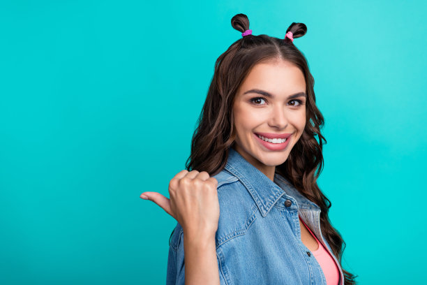 年轻可爱的女孩侧面照片，手指指向空白区域，适合用于折扣横幅，背景为青绿色。图片下载