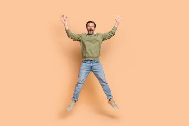 全身照片，兴奋满意的人跳起，双手举起，形成星形，背景为米色。图片下载