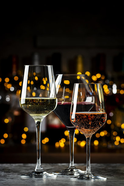 酒杯套装。红酒、白酒、玫瑰酒在深色背景下与酒瓶一起展示。酒吧、商店、品酒。图片下载