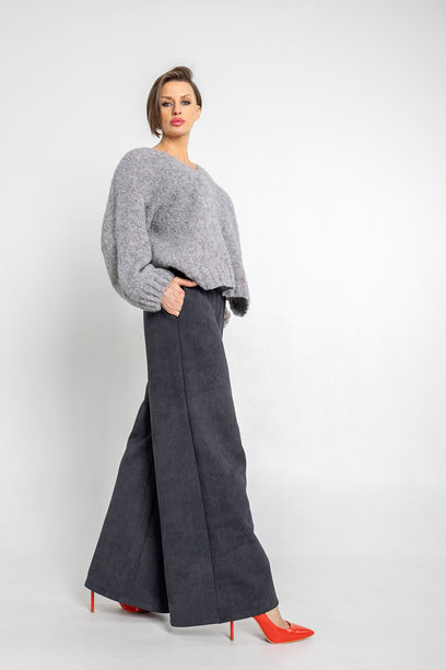 模特外貌的美丽女性肖像。女孩穿着灰色毛衣、黑色裤子，脚踩红色鞋子，背景为灰色。时尚妆容的漂亮女性在摄影棚中摆姿势。竖版照片图片下载