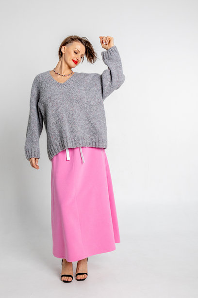 美丽的模特外貌女孩。穿着灰色毛衣和粉色裙子的快乐女性肖像。竖版照片图片下载