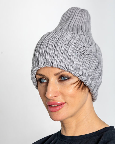 穿着温暖衣物的美丽女性，戴着灰色帽子。漂亮女孩在灰色背景下。摄影棚拍摄。竖版照片。图片下载