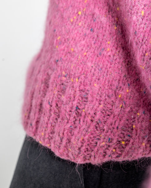 模特外貌的美丽女性肖像。女孩穿着粉色毛衣和黑色裤子，背景为灰色。竖版照片。图片下载