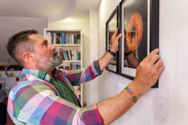 男人在家中墙壁上挂着装框的眼睛照片图片下载