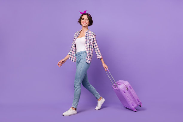 年轻漂亮女孩的全身侧面照片，走向注册航班出国旅行，背景为紫色。图片下载