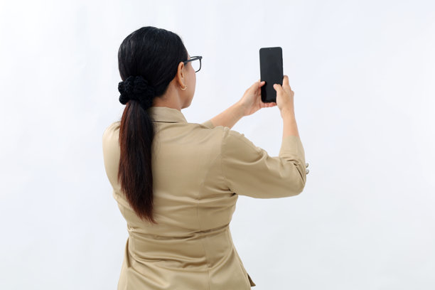 亚洲女公务员从后面拍摄手机照片。背景为白色。图片下载