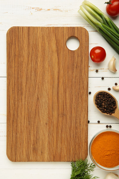 白色木质背景上的切菜板、青葱、大蒜、香料和西红柿。烹饪概念。竖版照片图片下载