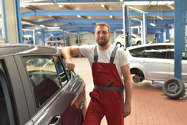 微笑的汽车修理工在专业车间的肖像 - 特写照片图片下载