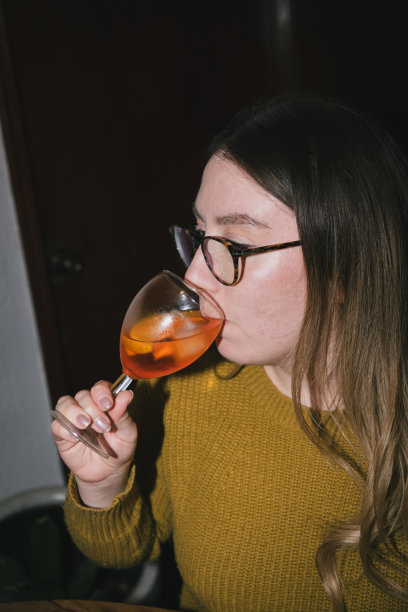 用户生成内容。个人档案照片。由真实人物拍摄的复古风格照片。快乐的女性在家中饮用鸡尾酒。图片下载