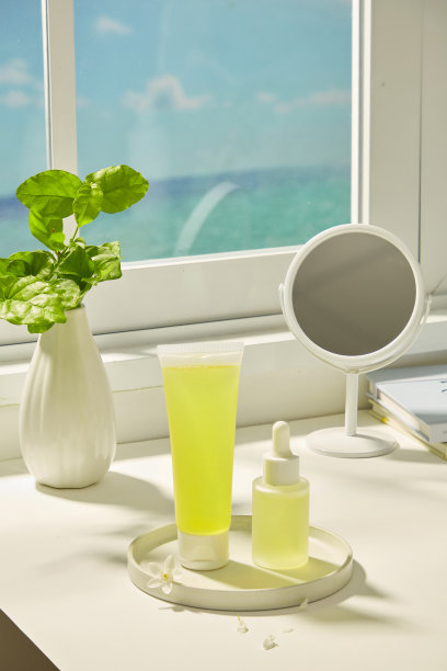 垂直照片显示放置在石板上的试管和滴管瓶。纤细的花瓶里插着绿叶。桌子上有镜子和书籍，旁边是窗户，窗外可以看到蓝天。图片下载