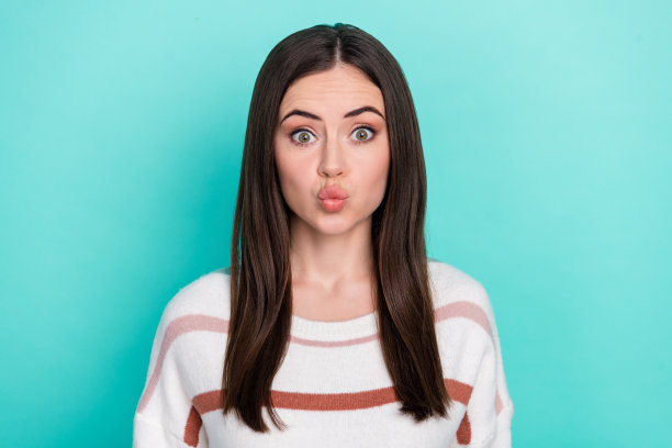 穿着条纹毛衣的幽默调皮女性在青绿色背景下向你送吻的照片图片下载