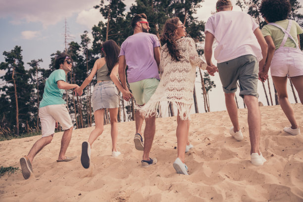 年轻公司员工在海滩户外一起休闲放松的全身背面照片，享受夏季假期散步。图片下载