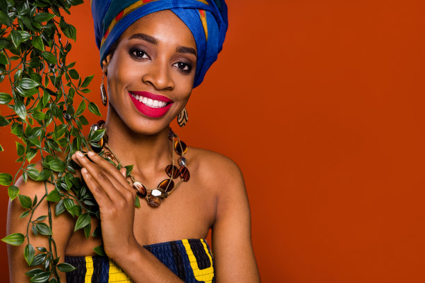 微距照片中微笑的美丽女士穿着传统服装，背景为空旷的棕色，周围是热带丛林。图片下载