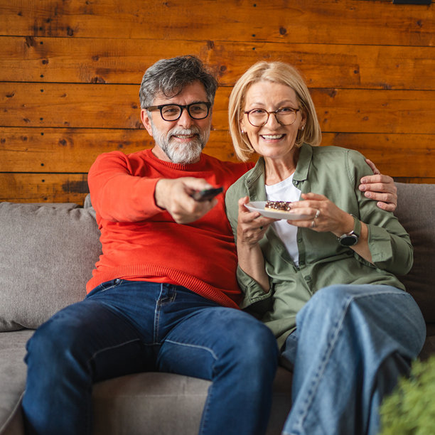 老人坐在沙发上看电视，女人在吃甜甜圈。图片下载