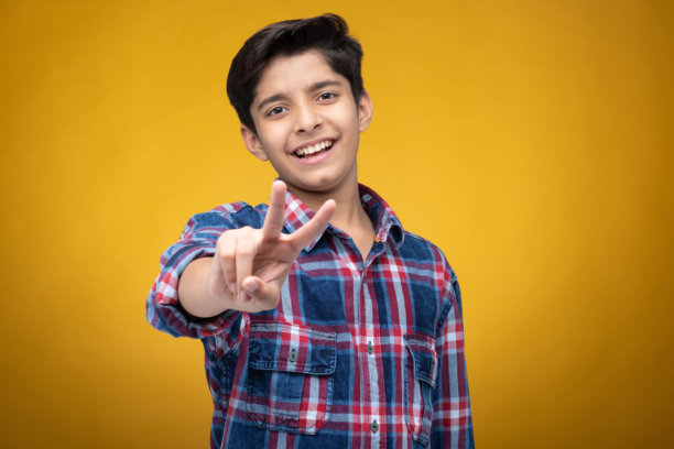 穿着格子衬衫的年轻男孩，背景为黄色，库存照片图片下载