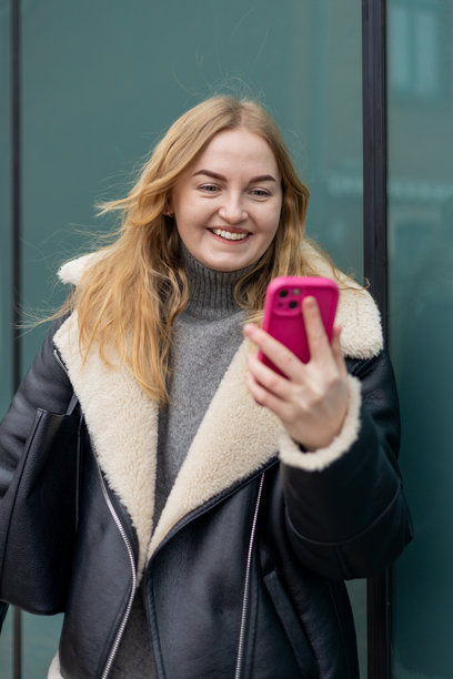 年轻时尚的30多岁女性在城市街道上走路时用智能手机写信息。都市生活方式概念。秋季时节。迷人的女性穿着时尚服装在线聊天。高质量照片。图片下载