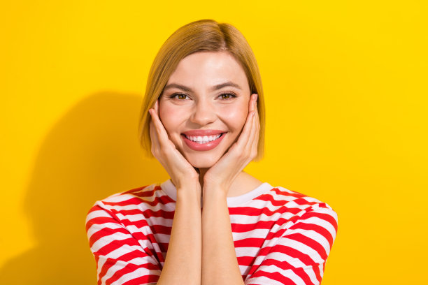 特写照片，快乐可爱的女孩穿着时尚的夏季服装，手臂触碰着颧骨，心情愉悦，背景为黄色。图片下载