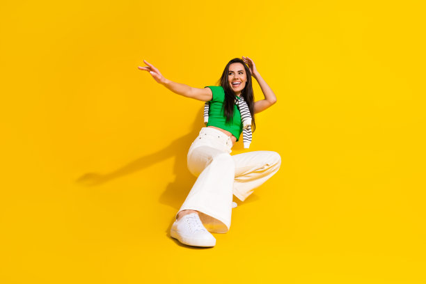 穿着绿色T恤的时尚女孩在黄色背景下尽情跳舞，享受乐趣的全身照片图片下载