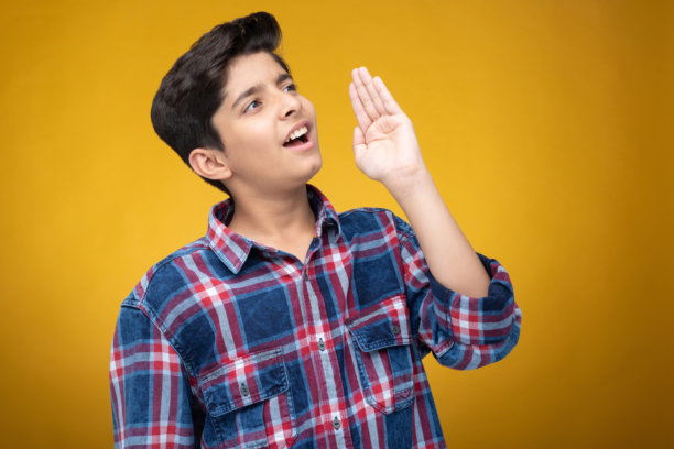 穿着格子衬衫的年轻男孩，背景为黄色，库存照片图片下载