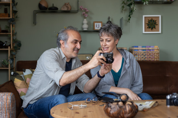 两位退休老人坐在沙发上研究一台复古相机。他们准备拍几张照片。图片下载