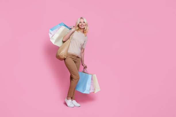 穿着时尚服装的可爱快乐女士的全身照片，秋季促销，粉色背景上有空白空间。图片下载