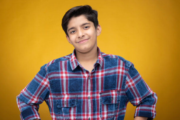 年轻男孩穿着格子衬衫，背景为黄色，库存照片图片下载